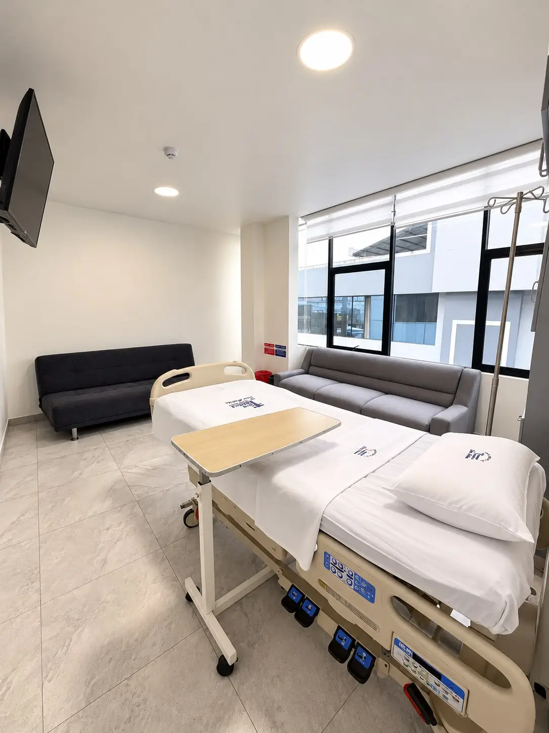 Una suite de hospitalización, con cama eléctrica y sofás junto a la ventana